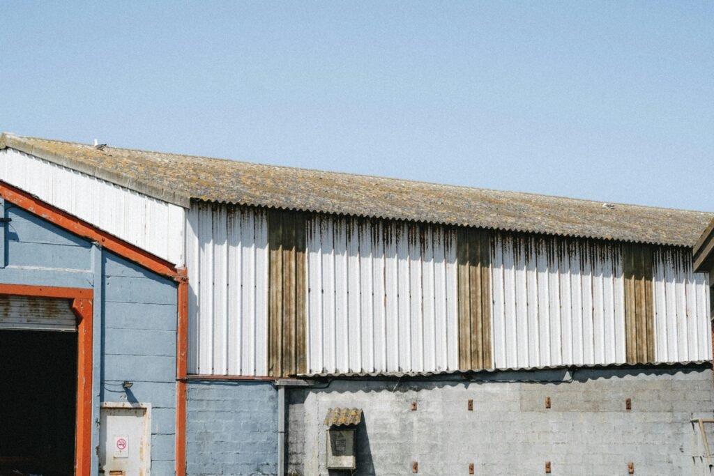 A weathered industrial building with corrugated metal siding and blue accents under a clear sky in Dunkerque, France.
